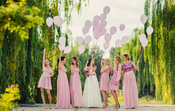 Eine Braut lässt mit ihren 6 Trauzeuginnen in rosa Kleidern Luftballons steigen