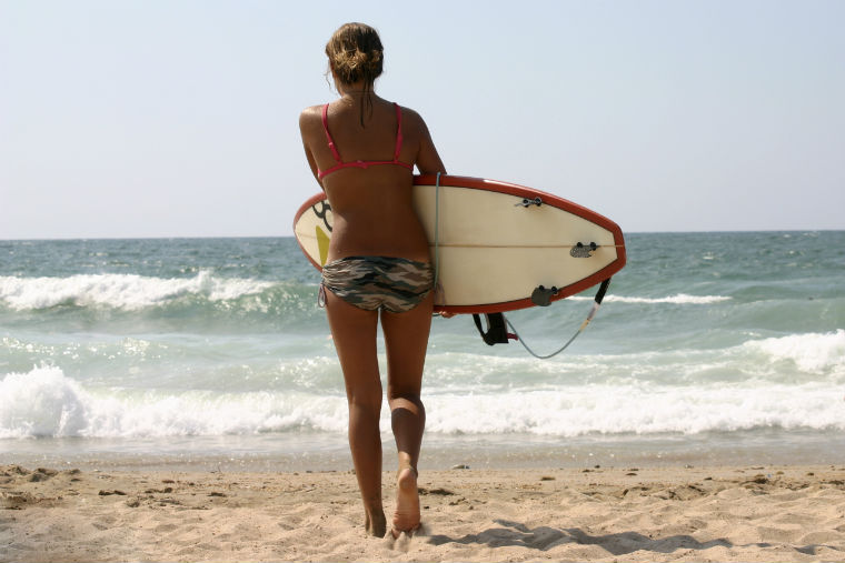 Frau mit Surfbrett am Strand 