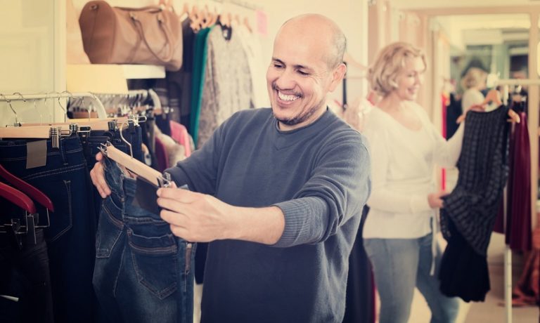Mann hält im Laden einen Jeanshose in der Hand