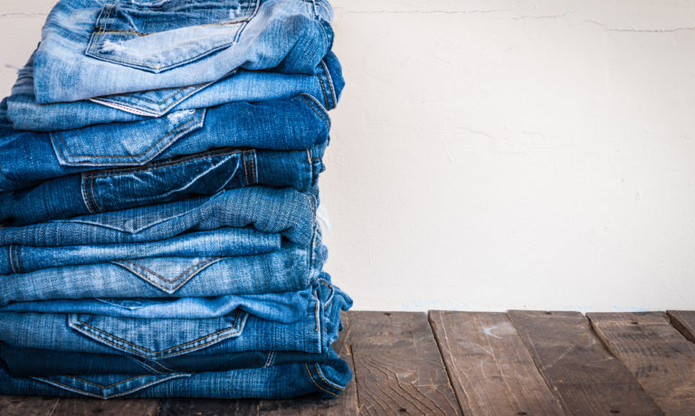 Ein Stapel aus Jeans-Hosen auf einem Holzgrund