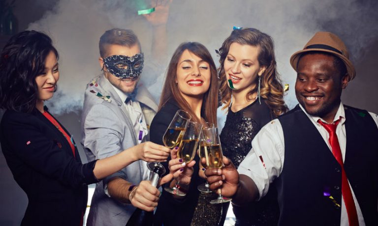 Fünf Personen stoßen im schicken Silvester Outfit mit Sekt an