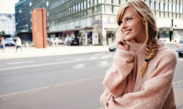 Frau, die einen rosa Pullover einer skandinavischen Modemarke trägt