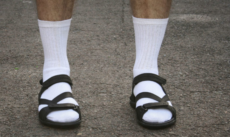 Mann, der weiße Tennissocken in Sandalen trägt