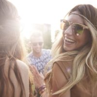Blondes Mädchen mit Sonnenbrille tanzt mit ihren Freunden auf einem Musik-Festival