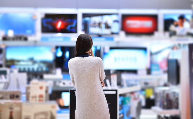 Frau steht vor einer großen Auswahl Fernseher